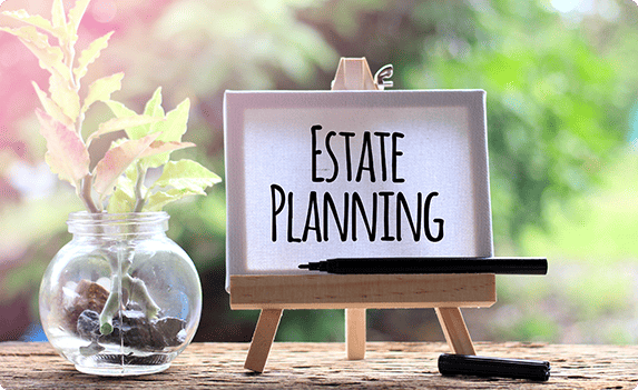 Estate planning sign on easel with pen and plant, legal preparation by Law Firm of Tammy W. Akers, LLC